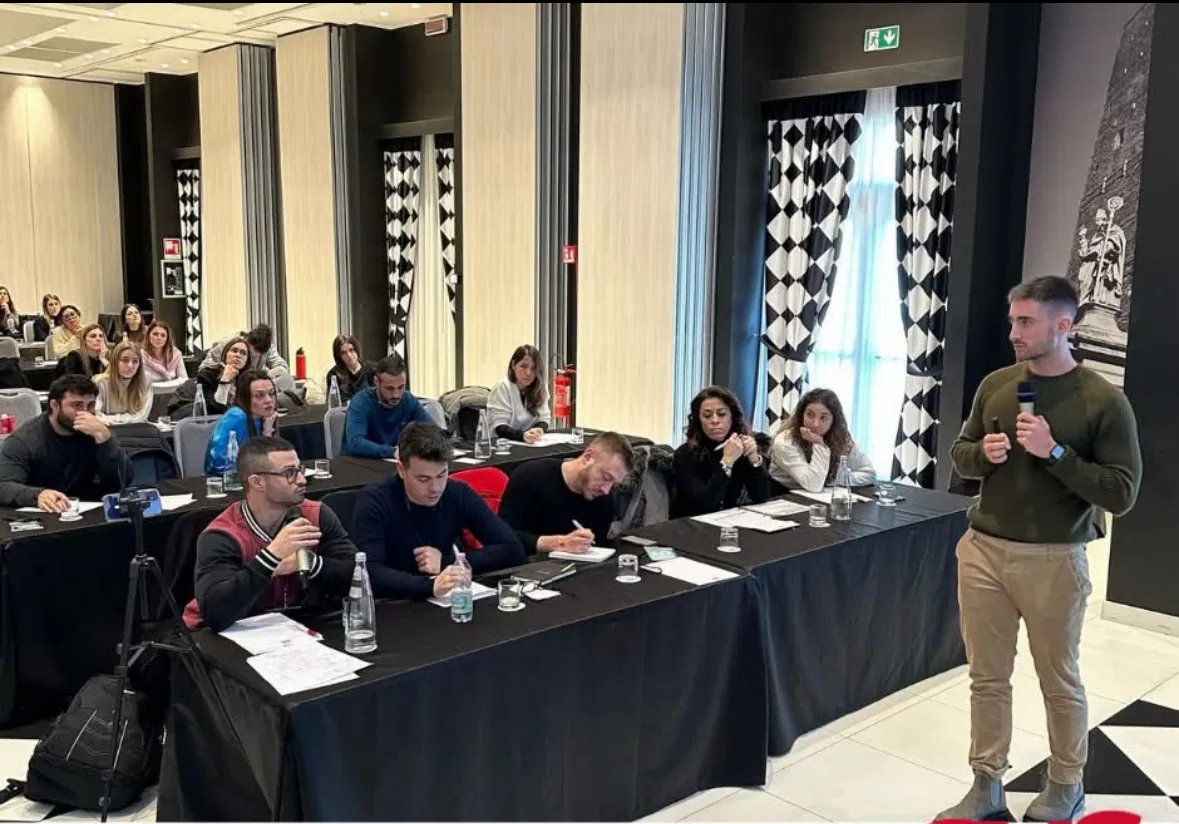 Lorenzo Candela parla con il microfono davanti a una sala piena di professionisti seduti ai banchi
