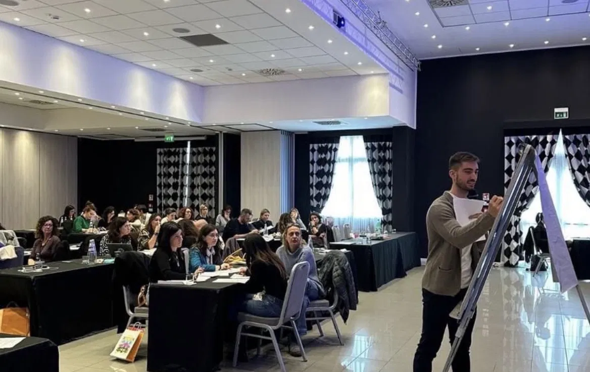 Lorenzo Candela scrive su una lavagna a fogli mobili davanti a una sala di professionisti